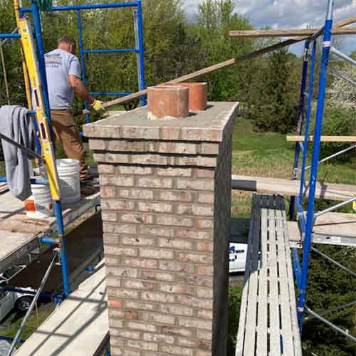 Aelite Chimney Crown Repairs-chimney with two flues and man on scaffolding